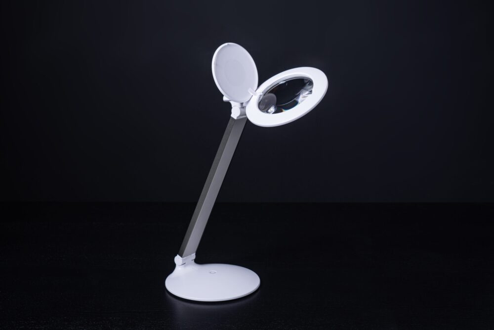 Lampe loupe rechargeable Daylight Halo Go 2, pliée et déployée, en utilisation pour travaux de précision.